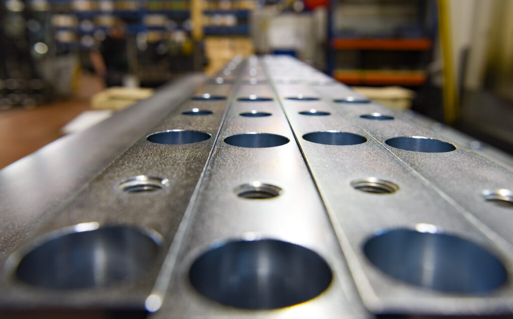Matt glänzende Metallbalken mit runden Löchern liegen aufeinander